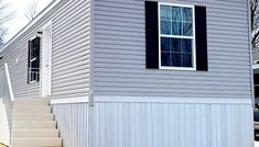 a small house with stairs leading up to it's front door and windows on the side