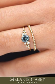 a woman's hand with two rings on top of her finger and the ring has blue