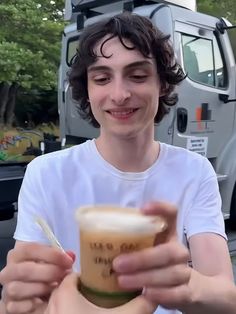 a young man is holding a drink in his hand