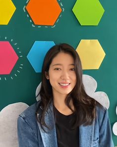 a woman standing in front of a wall with colorful hexagons on it