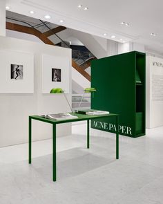 a green table sitting in the middle of a room with pictures on the wall behind it