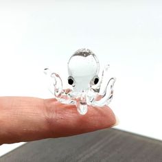 a small glass octopus sitting on top of a person's finger