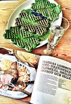 a plate with waffles, meat and vegetables on it next to an open book