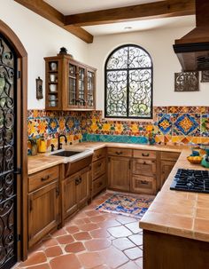 a kitchen with wooden cabinets and tile flooring in front of a large arched window