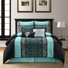 a bed in a room with two framed pictures on the wall and one has a blue and black comforter