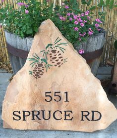 a stone sign that reads 551 spruce rd in front of some potted plants