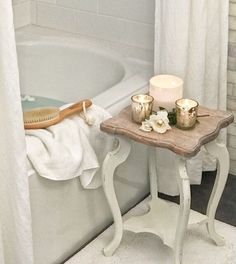 a white bath tub sitting next to a wooden table with candles on top of it