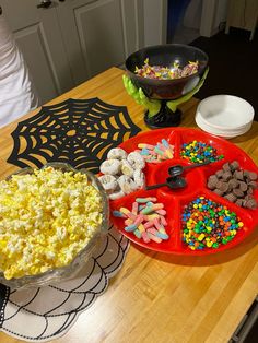 a table topped with plates and bowls filled with food next to a spider web decoration