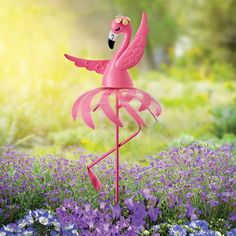 a pink flamingo standing in the middle of purple flowers