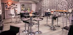 an empty restaurant with black and white wallpaper, bar stools and glass tables