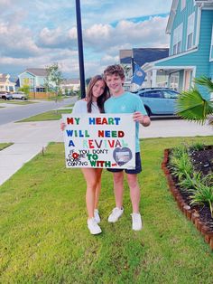 two people standing in the grass holding a sign