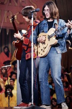 two people on stage playing guitars and singing