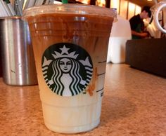 a starbucks drink sitting on top of a counter next to a cup with straws in it