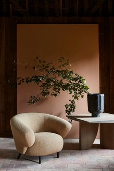 a chair and table with a plant in the corner next to it on a brick floor