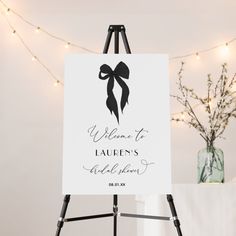 an easel with a welcome to lauren's wedding sign on it and lights in the background