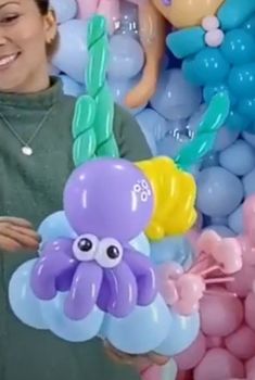 a woman holding an octopus balloon in front of balloons