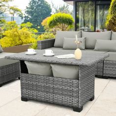 an outdoor patio furniture set with grey cushions and coffee table in front of a large window