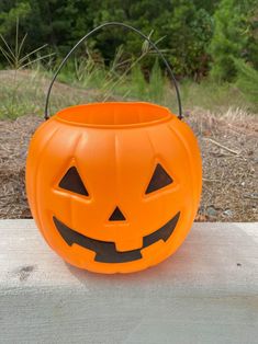 an orange halloween pumpkin bucket sitting on top of a wooden table