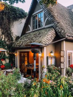 a small house with flowers and plants around it