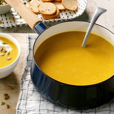 a bowl of soup with bread on the side next to it and a spoon in it