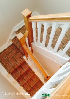 an overhead view of a stair case with wood handrails and carpeted flooring