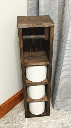 a wooden shelf with three rolls of toilet paper in it