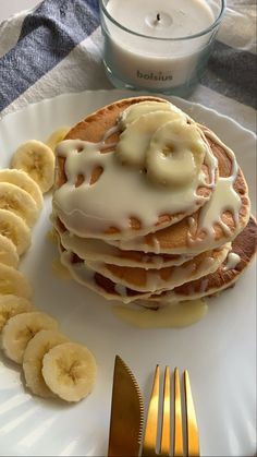 a plate topped with pancakes covered in icing next to sliced bananas