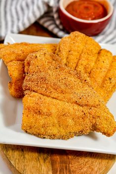 fried fish sticks on a white plate with dipping sauce