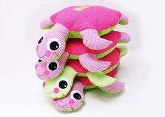 a pile of pink and green stuffed animals sitting on top of each other in front of a white background