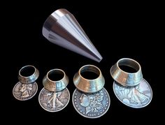 a set of five different types of coins and a silver cone on a black background