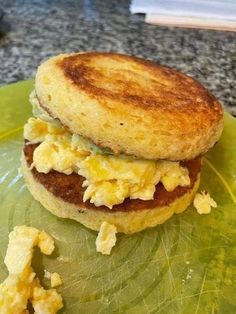 an egg and bacon breakfast sandwich on a green plate