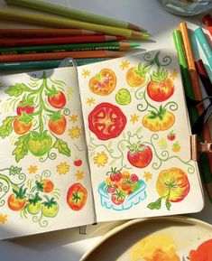 an open notebook with tomatoes on it next to some colored pencils and other art supplies