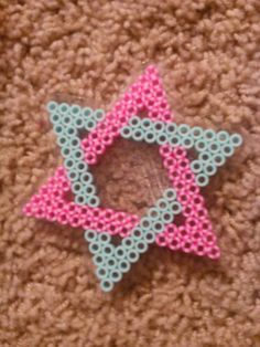 an ornament made out of plastic beads on carpeted area with pink and blue star