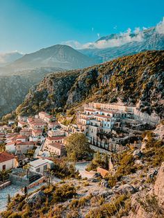 an aerial view of a village on the side of a mountain with mountains in the background