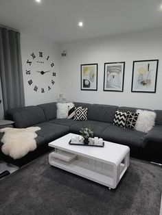 a living room with grey couches and white coffee table in front of two pictures on the wall