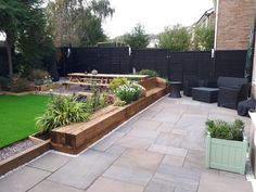 an outdoor garden area with grass, plants and wooden benches on the side of it