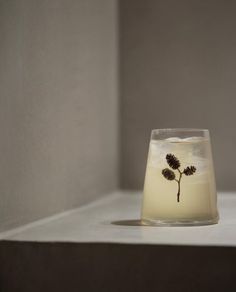 a small glass vase sitting on top of a white shelf with a flower in it