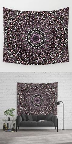 a black and pink tapestry hanging on the wall above a couch in front of a brick wall