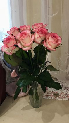 a vase filled with pink roses on top of a table