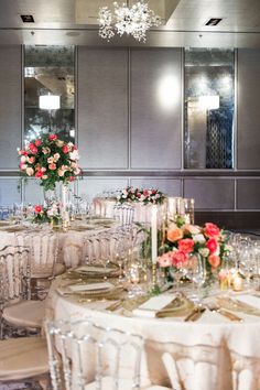 a dining room set up for a formal function with flowers and candles on the tables