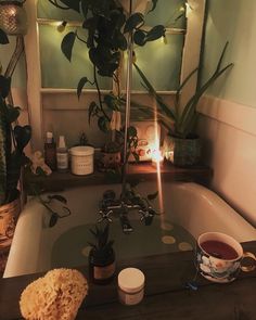 a bathroom sink with plants and candles on the counter