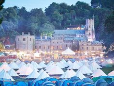 many tents are set up in front of an old building at night with lights on them