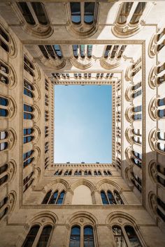 looking up at the sky through an arch in a building's facade with windows