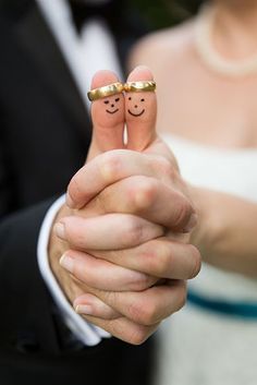 a couple holding hands with two fingers painted like faces on each finger and the bride's wedding ring