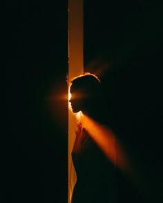 a woman standing next to a tall pole in the dark with her head turned back