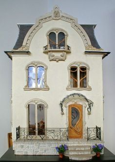 the doll house is made out of white clay and has windows, doors, and balconies