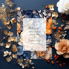 a wedding card surrounded by flowers and leaves on a dark blue background with gold foil