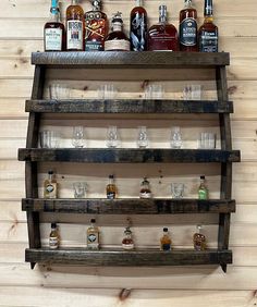 a wooden shelf filled with bottles and glasses on top of a wall covered in wood planks