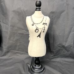 a mannequin wearing a white dress with black beads and a necklace on it