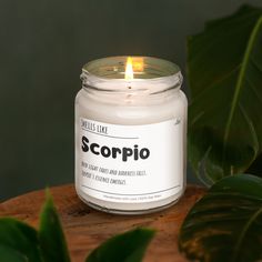 a candle that is sitting on top of a wooden table next to some plants and leaves